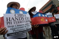 FILE - Filipino student activists hold mock Chinese ships to protest recent island-building and alleged militarization by China off the disputed Spratlys group of islands in the South China Sea, during a rally in Manila, Philippines, March 3, 2016.