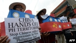FILE - Filipino students hold replicas of Chinese maritime surveillance ships as they shout anti-Chinese slogans during a rally in Manila March 3, 2016, to denounce reported Chinese vessels dropping anchor near a South China Sea atoll.