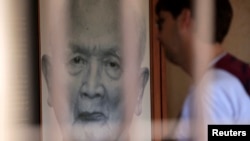 A tourist looks at a portrait of former Khmer Rouge leader "Brother Number two" Nuon Chea at the Tuol Sleng Genocide Museum in Phnom Penh August 2, 2014. Cambodia's young population is very aware of its grim history, with almost every family suffering losses. Most Cambodians still want justice and to see the U.N.-backed court find the recalcitrant Nuon Chea, Pol Pot's right-hand man, and ex-President Khieu Samphan, guilty of crimes against humanity, but the court has been mired in disputes, resignations, funding shortages and accusations of political interference and has to date delivered just one verdict.