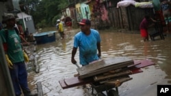 Para warga membereskan barang-barang di rumah mereka yang terendam banjir di Itapetinga, Bahia, Brazil, pada 28 Desember 2021. (Foto: AP/Raphael Muller)