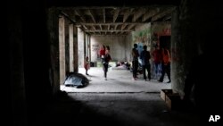 FILE - A migrant woman walks with her baby in a makeshift migrant camp in Bihac, 450 kms northwest of Sarajevo, Bosnia, Aug. 14, 2018. 