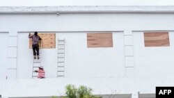 Para pekerja bersiap menghadapi badai Nana dengan menutupi jendela sebuah toko, di Belize City, Belize, 2 September 2020. (Foto oleh JOSE A . SANCHEZ / AFP).