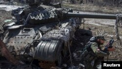 16일 우크라이나 동부 도네츠크 외곽 스파르타크 지역에서 반군 병사가 손상된 정부군 탱크 앞에 앉아 있다.