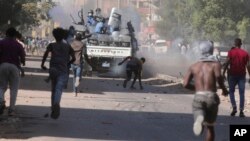 FILE - Young men confront the police during a protest against a military coup that ousted a civilian government, in Khartoum, Sudan, Nov. 17, 2021. 