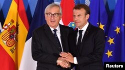 FILE - European Commission President Jean-Claude Juncker, left, shakes hands with French President Emmanuel Macron during an informal EU summit on migration at EU headquarters in Brussels, Belgium, June 24, 2018.