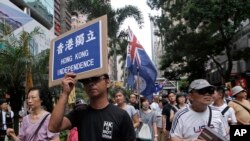 FILE - Protesters hold placards and wave colonial-era flags at an annual pro-democracy rally in Hong Kong, July 1, 2016. As the territory prepares for legislative elections, a new pledge of loyalty to China candidates are required to sign is creating friction.