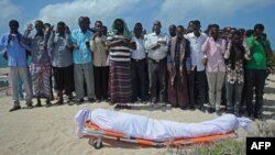 FILE - Relatives and fellow journalists pray as they stand next to the body of Somali journalist Abdulaziz Ali Haji during his funeral, Sept. 28, 2016, in Mogadishu. 