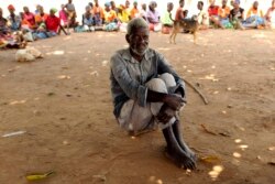 A man waits to receive food aid outside a camp for displaced survivors of cyclone Idai in Dombe, Mozambique, April 4, 2019.