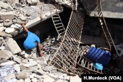 FILE - A boy searches for human remains under the rubble of his Old Mosul neighborhood in Mosul, Iraq, May 9, 2018.