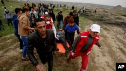 Medics and protesters evacuate a youth who was shot by Israeli troops near the Gaza Strip's border with Israel while marking first anniversary of Gaza border protests east of Gaza City, March 30, 2019.