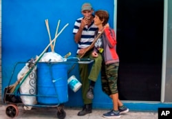 In this April 3, 2018 photo, street cleaners take a break as they work on the main boulevard in Holguin, Cuba.