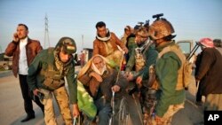 FILE - Kurdish soldiers help move an elderly Yazidi who was released by Islamic militants in Kirkuk, Iraq, Jan 17, 2015.