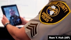 In this Friday, Aug. 13, 2021, photo Sheriff's Police Sgt. Bonnie Busching tests a video meeting with a personal electronic device at the Cook County Sheriff's Office in Chicago. (AP Photo/Nam Y. Huh)