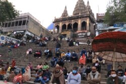 Tourists sit at the Asi Ghat of Varanasi above the banks of the Ganges river in Varanasi, India. Hundreds of thousands of Indian and foreign tourists visit Varanasi and its ghats every year. (Praveen Joshi/VOA)