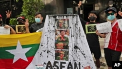 Activists display posters and defaced portraits of Myanmar's Commander-in-Chief Senior General Min Aung Hlaing during a rally against the military coup in Jakarta, Indonesia, April 24, 2021.