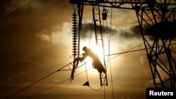 A technician works on an electricity pylon as part of maintenance of high-tension electricity power lines, during sunset in Roye, France, February 11, 2019. 
