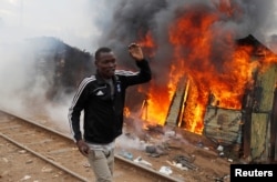 A supporter of opposition leader Raila Odinga runs past a burned shack, in Kibera slum, Nairobi, Kenya, Aug. 12, 2017.