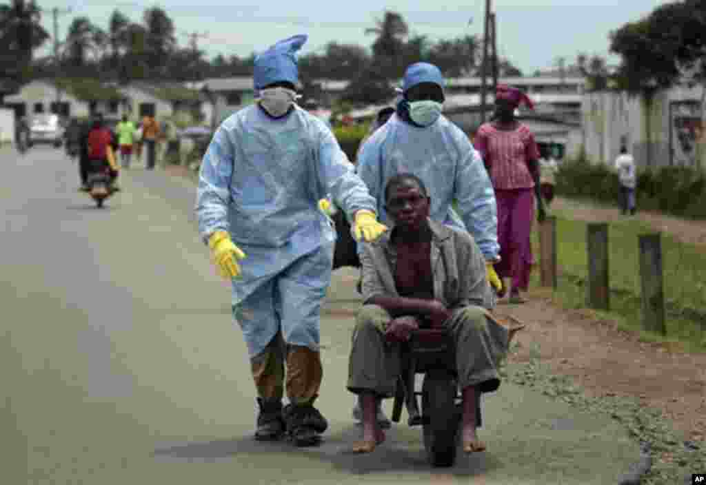 Les habitants du quartier Saint-Paul Pont couverts d&rsquo;un équipement de protection individuelle transportent un homme soupçonné de porter le virus Ebola à la Clinique île à Monrovia, au Libéria, le dimanche 28 septembre 2014.Six months into the world&rsquo;s worst-ever Ebola outbreak, a 