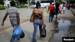 FILE - People cross to Venezuela over the Simon Bolivar bridge after shopping in Cucuta, Colombia, Dec. 1, 2016. Many Venezuelan women are selling their hair in Colombia in reaction to their country's struggling economy. 