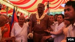 The mother (L) and a sister of slain political analyst Kem Ley move his statue at his hometown in Takeo province, Sunday, October 15, 2016. (Leng Len/VOA Khmer)