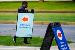 FILE - A worker posts placard for a COVID-19 vaccination clinic at the Reading Area Community College in Reading, Pa, Sept. 14, 2021.