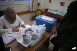 A Palestinian woman has her child checked at an UNRWA-run clinic in the Shati refugee camp, Gaza City, Jan. 14, 2018.