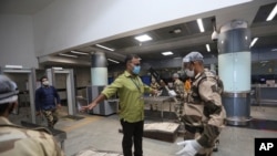 An Indian paramilitary soldier wearing protective gear frisks journalists during a press preview to show the preparedness of Delhi Metro at a station in Delhi, India, Sept. 3, 2020.