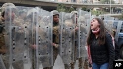 A protester shouts slogans in front of army soldiers during a protest against a parliament session vote of confidence for the new government in downtown Beirut, Lebanon, Feb. 11, 2020. 