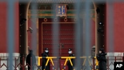 Security guards wearing protective face masks stand guard at the closed gates of the Forbidden City, in Beijing, April 19, 2020.