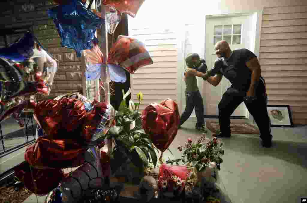 Walter Farrow Jr., right, of Birmingham, Ala., strikes a boxing pose with Malachi Chism, 10, of Louisville, Ky., on the porch of Muhammad Ali's boyhood home in Louisville the night before Ali's funeral and memorial services, June 9, 2016.