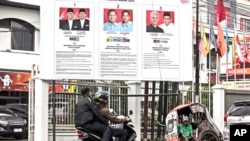 Seorang pengemudi becak menunggu pelanggan di depan poster pilpres 2024 di Medan, Sumatera Utara, 13 Februari 2024. (Foto: Binsar Bakkara/AP Photo)