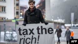 Austrian Marlene Engelhorn, whose family owns Germany's chemical giant BASF, poses with a placard reading "Tax the rich!" at the entrance of the Congress center on the opening of the annual meeting of the World Economic Forum in Davos, on Jan. 15, 2024. 