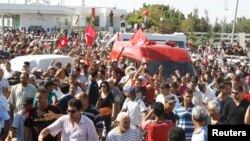 People walk beside the ambulance carrying the body of assassinated Tunisian opposition politician Mohamed Brahmi in Tunis, July 25, 2013. 