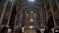 People wearing face masks to prevent the spread of COVID-19 pray in John Paul II chapel in St. Peter's Basilica at the Vatican in the day of its reopening which coincided with John Paul II 100th anniversary of birth, May 18, 2020. 