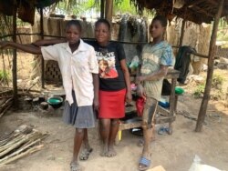 Nayigga Rashidah stands with two of her children in front of their makeshift restaurant in Ntawo village, Mukono district Uganda, Aug. 1, 2020. (Halima Athumani/VOA)