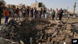 Warga sipil memeriksa lubang besar akibat ledakan bom mobil bunuh diri di sebuah pasar yang ramai di Khan Bani Saad, provinsi Diyala province, 30 kilometer dari Baghdad, Irak (18/7).