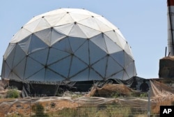 Two silhouetted Israeli soldiers, bottom right, stand next to a dome protecting radar gear as they look toward journalists during a media trip organized by Hezbollah to illustrate defensive measures established by Israel at the Lebanese-Israeli border near the Labbouneh, south Lebanon, April 20, 2017.