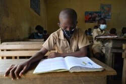 A child wears a face mask while he reads in a classroom in Abidjan on May 25, 2020 on the first day day after resumption of classes after COVID-19 coronavirus lockdown