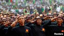 Members of Banser, the security unit of Indonesia's largest Muslim organization, Nahdlatul Ulama (NU), salute guests during a parade to commemorate the organization's 85th anniversary in Gelora Bung Karno Stadium in Jakarta, July 17, 2011. 