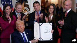 صدر ڈونلڈ ٹرمپ بدھ، 29 جنوری، 2025 کو واشنگٹن میں وائٹ ہاؤس کے ایسٹ روم میں ایک تقریب کے دوران لیکن رائلی ایکٹ پر دستخط کرنے کے بعد دستاویز دکھا رہے ہیں۔ (اے پی فوٹو)