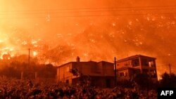 FILE - A wildfire approaches houses in the village of And Loutro, south of Athens, Greece, Sept. 30, 2024. 