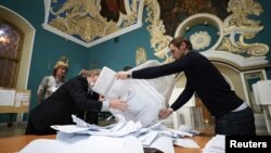 Anggota komisi pemilihan lokal mengosongkan kotak suara sebelum mulai menghitung suara setelah pemungutan suara ditutup, di sebuah tempat pemungutan suara di dalam terminal kereta api Kazansky di Moskow, 19 September 2021. (Foto: Reuters)
