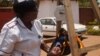 FILE - Charity Salima weighs a child at Achikondi Community Clinic in Lilongwe, Malawi. (Lameck Masina/VOA)