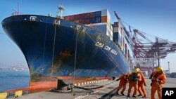 চীনের শান্ডং প্রদেশের চিংডাও বন্দরে শ্রমিকরা একটি কন্টেইনারবাহী জাহাজ ডকে ভেড়াচ্ছে। ফাইল ফটোঃ ১১ ফেব্রুয়ারি, ২০২৪। 
