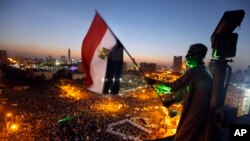 An Egyptian protester waves a national flag over Tahrir Square, the focal point of Egyptian uprising as opponents of President Mohamed Morsi are gathered in Cairo, June 28, 2013.