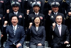 FILE - Taiwan's President Tsai Ing-wen, center, along with Defense Minister Feng Shih-kuan, right, and Secretary-General of National Security Council Joseph Wu, left, cheer with navy officers during a visit to Zuoying Naval base in Kaohsiung, southern Taiwan.