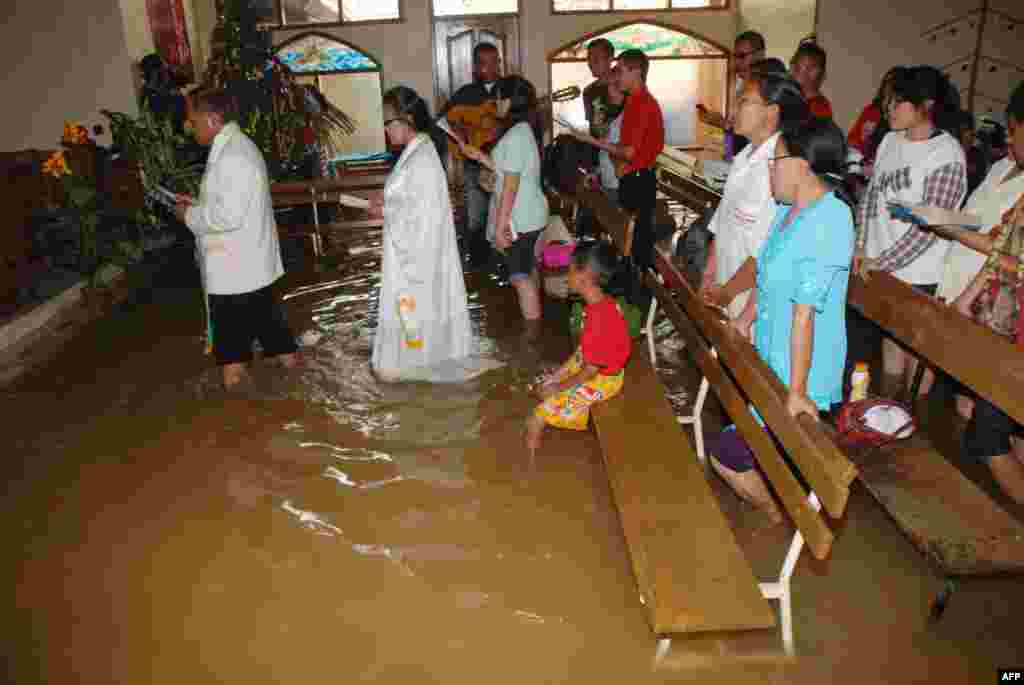 Warga Kristen menghadiri misa Natal di sebuah gereja yang terkena banjir di Bandung, Jawa Barat, Indonesia (25/12).