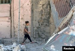 A girl walks on debris in a rebel-held part of the southern city of Deraa, Syria, July 9, 2017.