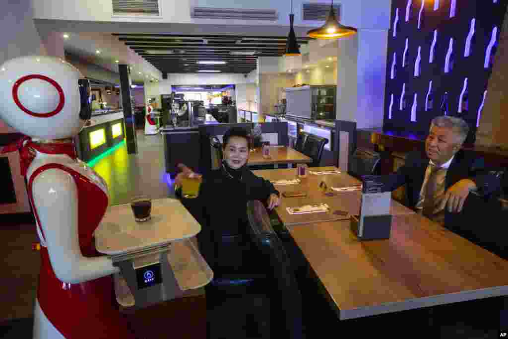 Owners Shu Lei Hu, left, and her husband Shao Song Hu, right, demonstrate the use of robots for serving purposes or for dirty dishes collection at the family&#39;s Royal Palace restaurant in Renesse, south-western Netherlands, Wednesday, May 27, 2020. (AP Pho