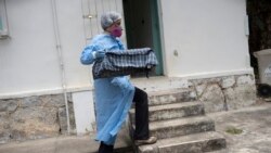 A researcher for Brazil's state-run Fiocruz Institute, wearing protective gear, transports captured monkeys to a holding area, at Pedra Branca state park, near Rio de Janeiro, Tuesday, Oct. 29, 2020. (AP Photo/Silvia Izquierdo)